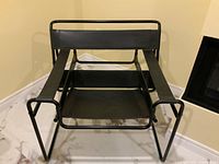 Front view of chair showing black tubular steel frame and leather sling seat.