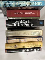 Photo of nine hardcover books stacked with spines visible including 'Men, Ships, and the Sea,' 'The Caine Mutiny,' and others.