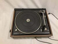 Front angled view of the Dual 502 turntable showing the platter, tonearm with cartridge, speed selector, and wooden base. Power cord visible.