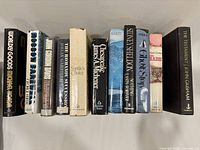 Front view of the 12 hardcover books showing titles and authors on the spines, arranged upright.