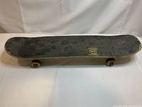 Top view of skateboard showing heavily used black grip tape with wear and damage