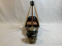 Front view of ship showing the pirate skull bank in front with blue eyes, the ship's bow and mast rigging in the background