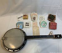 Complete view of banjo lying flat alongside scattered vintage string envelopes