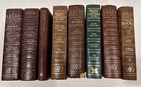 Image shows 10 volumes of vintage Reader's Digest Condensed Books standing upright, with faux leather bindings in burgundy, chestnut, and forest green earth tones, gold embossed spines and titles.