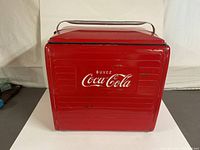 Front view of the red 1958 Coca-Cola cooler with embossed Coca-Cola logo and 'Buvez' text.