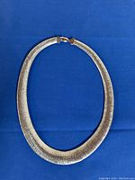 Full front view of necklace laid flat on blue background