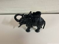 Side view of cast elephant coin bank showing details of textured cast metal and coin holding saddle.