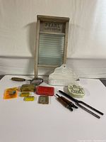 Front view of small Pearl glass washboard with surrounding vintage tins, tools, and a white metal wall holder.