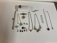 Full lot overview showing various silver jewelry pieces including bracelets, rings, pendants, pins, and necklaces.