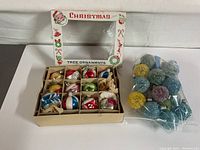 Overview of the box with 12 assorted vintage glass Christmas bulbs and sealed bag of sugarplum bulbs