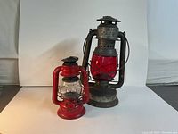 Photo shows both vintage Dietz lanterns, a smaller red Comet lantern and a larger gray Beacon lantern with a red glass globe.