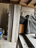 Four weathered wooden barn boards standing upright showing their full length and width.