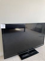 50 inch Toshiba television showing most of the screen and base stand from a side angle, remote on the base stand