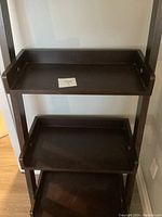 Full view of shelf unit showing dimensions and angled shelves with rails and handles.