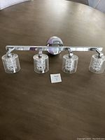 Full view of the 4-bulb chrome bathroom vanity light fixture laid on a table.