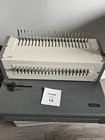 Front view of heavy duty binding machine showing metal punching pins, lever, and base.