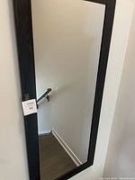 Full view of the black framed wall mirror showing its rectangular shape and reflective surface