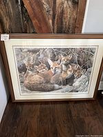 Full view of the framed print showing five foxes resting among rocks and tree roots with a wooden frame.