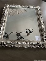 Full view of the rectangular silver mirror showcasing the reflective glass and the detailed ornate frame