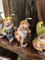 Close-up of 3 Disney 7 Dwarfs figurines on forest path base, showing detailed expressions and pickaxes