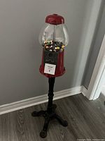 Full view of gum ball machine on black ornate stand showing approximate height and overall condition