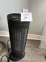 Full front view of black tower heater showing vent grille and base on floor