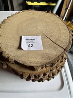 Top view of stacked wood rounds showing circular growth rings and some missing bark on edges.