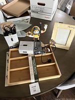 Full view of the lot showing the M&M character radio, bamboo organizer, ceramic picture frame, and pendant light boxes on a table.