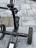 Angled side view showing tubular frame, remote control attached to handlebar, charger unit mounted on lower support