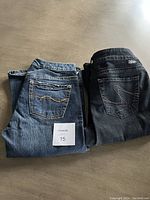 Two pairs of jeans folded side by side showing back pockets and stitching details