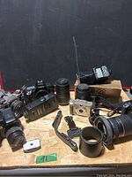 Overview image of the lot showing multiple Canon cameras, lenses, flash units and accessories arranged on a table.