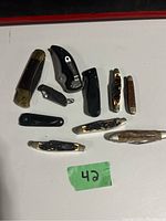 Image showing all nine knives and folding pocket tools laid out on white surface.