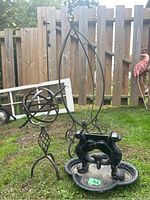 Photo showing dog-shaped cast iron statue with tray and part of hanging basket holder with ornate base.