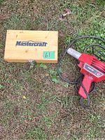 Wooden case with Mastercraft logo and Master Appliance heat gun sitting on grass.