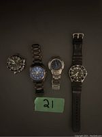 Image showing 4 men's watches placed side by side on a gray background with a green label marked '21'.