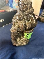 Front and side view of bronze-colored figurine showing an Eskimo child in fur-trimmed hood and jacket holding a dog.