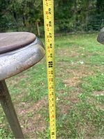 Close-up photo showing height measurement of one stool at approximately 27.5 inches, focusing on round wooden seat and metal rim.