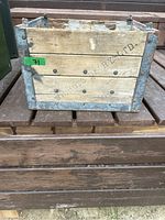 Front view of wooden crate marked Wilmots Dairy Ltd with metal joined corners