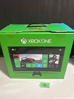 Closed original green Xbox One box with front displaying console UI screen including Forza Motorsport 5 tiles.