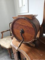 Angled view of barrel churn on wooden sideboard with floral upholstered chair in background