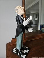 Side view of the butler figurine wine bottle holder showing detailed facial features, tuxedo jacket, and checkered base.
