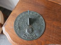 Top view of round metal sundial with embossed sun face and hour markers.