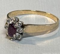 Front-angle view of ring showing floral cluster setting with red center and clear accent stones