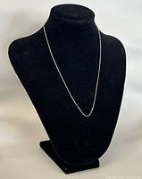 Full view of chain draped on black bust form.