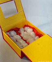 Image showing all four pale Hetian jade carved mini statues inside the red and yellow presentation box lined with red fabric.
