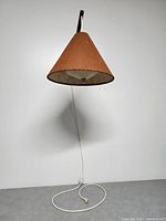 Front view of the lamp mounted on the wall showing the burlap shade and cord hanging down to the plug.