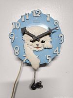 Front view of the rare 1960s Spartus cat wall clock showing its blue circular face with prominent white cat figure and large numbers.