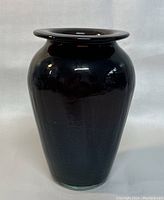 Front view of the signed art glass vase showing its rounded shape and glossy dark finish.