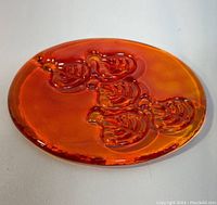 Top view of the bright orange glass suncatcher showing the embossed leaves design and glossy finish.