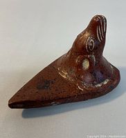 Photo of the vintage Aztec clay figure showing its top and side profile with visible painted animal facial features and speckled terracotta surface.